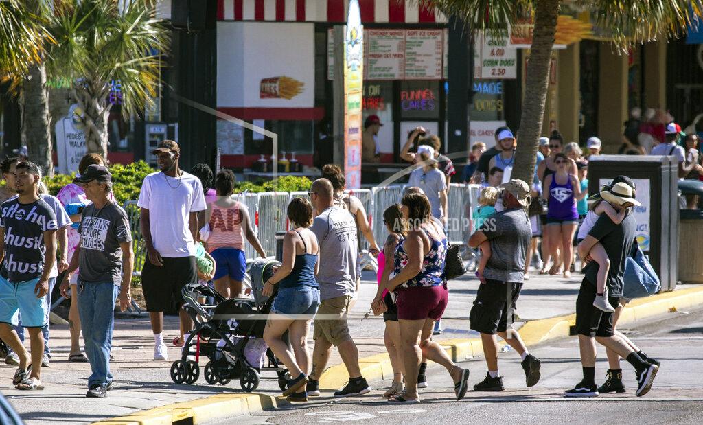 Groups cross Ocean Boulevard on Saturday, May 16, 2020 in Myrtle Beach, S.C.. With hotels, beaches, shopping and restaurants reopening along the Grand Strand, tourist season kicked off this weekend despite coronavirus concerns. (Jason Lee/The Sun News via AP)