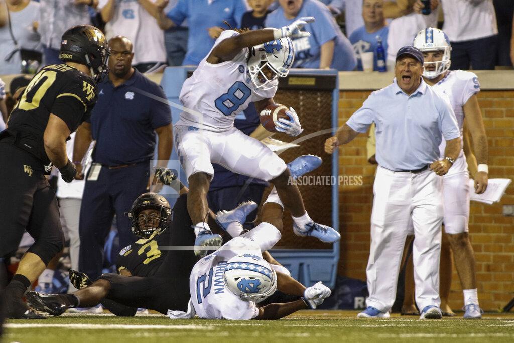 North Carolina running back Michael Carter (8) leaps over Wake Forest defensive back Nasir Greer (3) and North Carolina wide receiver Dyami Brown (2) during the second half of an NCAA college football game in Winston-Salem, N.C., Friday, Sept. 13, 2019. Wake Forest won 24-18. (AP Photo/Nell Redmond)