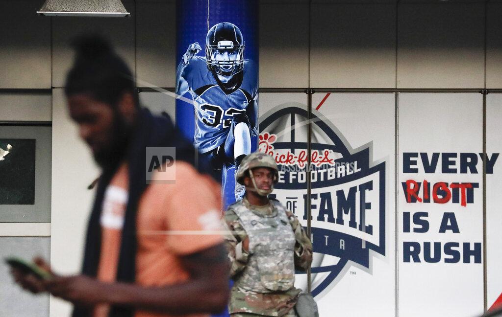 Brynn Anderson A member of the national guard stands in front of a sign the reads "Every Riot Is A Rush" in the aftermath of a demonstration against police violence on Saturday, May 30, 2020, in Atlanta. (AP Photo/Brynn Anderson)
