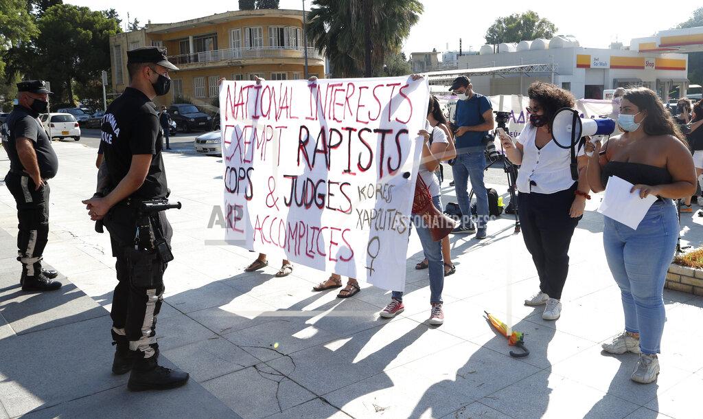 Philippos Christou Protesters hold a banner in support of a British woman who is appealing her conviction for making false claims that she was gang raped by as many as a dozen Israelis, as police officers stand guard in front of Cyprus' Supreme Court in the capital Nicosia on Thursday, Sept. 16, 2021. Lawyers for the British woman sentenced to a four-month suspended sentence for making up the gang rape claims during a 2019 Cyprus holiday are appealing to the country's Supreme Court to overturn the conviction. (AP Photo/Philippos Christou)