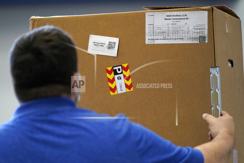Robert F. Bukaty A worker moves a box of needles and other medical supplies a day ahead of the launching of a new community COVID-19 vaccination clinic at the Portland Expo, Monday, March 1, 2021, in Portland, Maine. (AP Photo/Robert F. Bukaty)