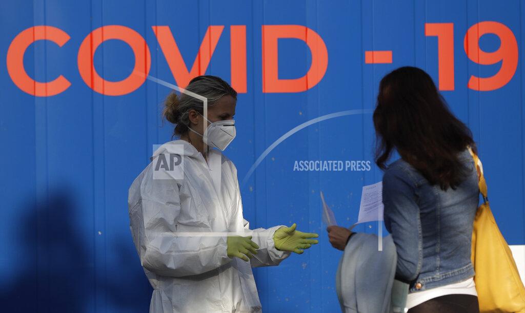 Petr David Josek A woman talks to a healthcare worker before getting tested for COVID-19 at a sampling station in Prague, Czech Republic, Monday, Sept. 21, 2020. The country coped well with the first wave of the coronavirus infections in the spring but has been facing a record surge of the new confirmed cases last week. (AP Photo/Petr David Josek)