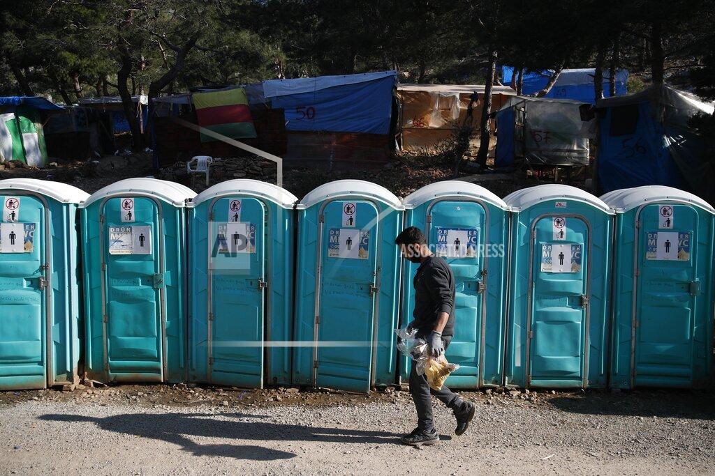 Thanassis Stavrakis A migrant walks in front of chemical toilets outside the perimeter of the overcrowded refugee camp at the port of Vathy on the eastern Aegean island of Samos, Greece, Wednesday, Feb. 24, 2021. On a hill above a small island village, the sparkling blue of the Aegean just visible through the pine trees, lies a boy’s grave. His first ever boat ride was to be his last - the sea claimed him before his sixth birthday. His 25-year-old father, like so many before him, had hoped for a better life in Europe, far from the violence of his native Afghanistan. But his dreams were dashed on the rocks of Samos, a picturesque Greek island almost touching the Turkish coast. Still devastated from losing his only child, the father has now found himself charged with a felony count of child endangerment. (AP Photo/Thanassis Stavrakis)