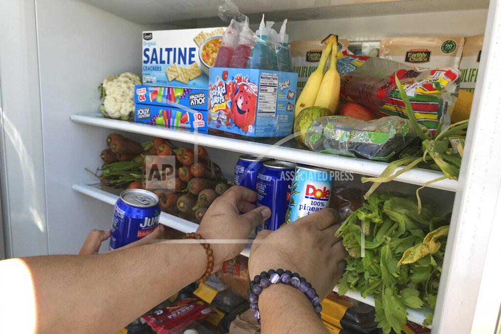 Aron Ranen Volunteers stock a refrigerator with free food for people in need in Los Angeles on July 20, 2020. A network called, LA Community Fridge, has placed eight of across the Los Angeles area, from the Highland Park neighborhood north of downtown to Exposition Park near the University of Southern California to the seaside city of Long Beach, with plans to install more. (AP Photo/Aron Ranen)