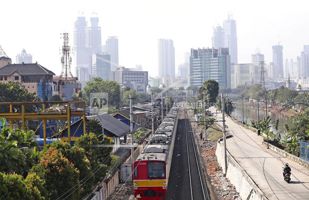 Tatan Syuflana A train moves down its track as the hazy city skyline is seen in the background in Jakarta, Indonesia, Thursday, Sept. 16, 2021. An Indonesian court ruled Thursday that President Joko Widodo and six other top officials have neglected to fulfill citizens' rights to clean air and ordered them to improve the poor air quality in the capital. (AP Photo/Tatan Syuflana)