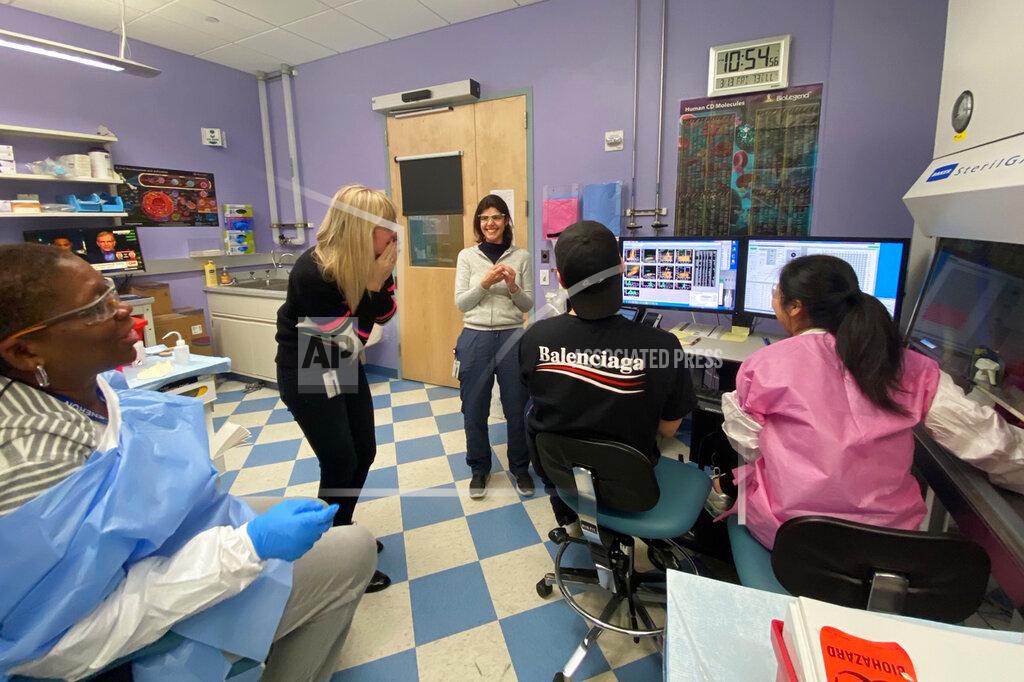 Uncredited In this Friday, March 13, 2020 photo provided by Regneron, members of the Infectious Disease team celebrate at their lab in New York state after confirming cells from Singapore are viable and that some make antibodies that bind to the coronavirus, suggesting they may have the potential to block it. (Regeneron via AP)