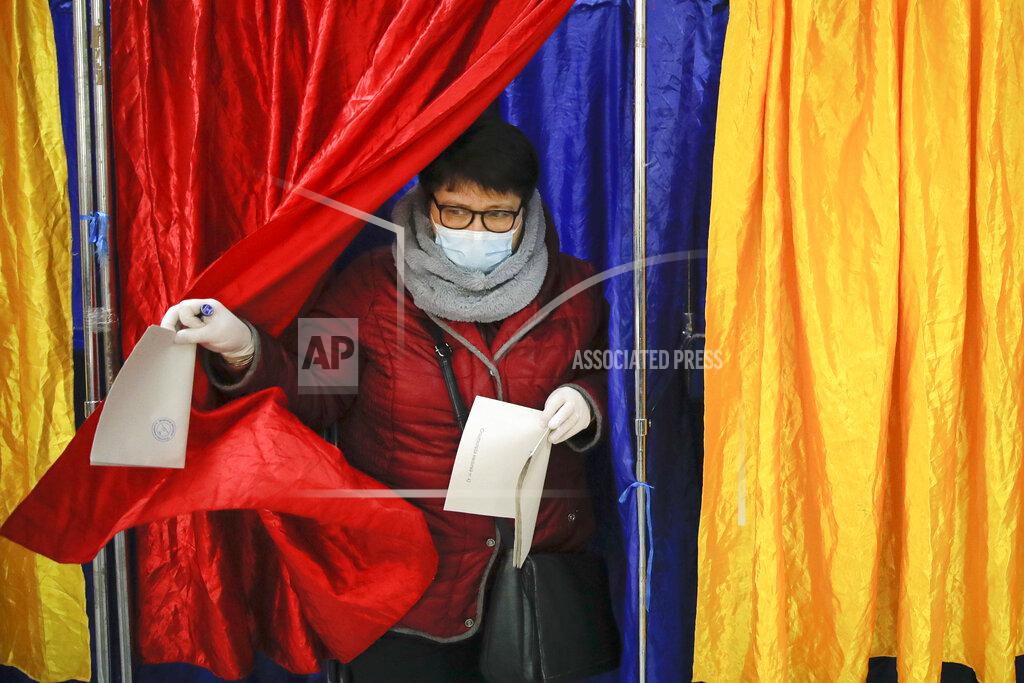 Vadim Ghirda A woman wearing a mask for protection against the COVID-19 infection exits a voting cabin in Bucharest, Romania, Sunday, Dec. 6, 2020. Voting started in Romania's legislative election expected to restore some measure of stability after five years of political and social turbulence with more than 18 million Romanians registered to vote for a new legislative body. (AP Photo/Vadim Ghirda)
