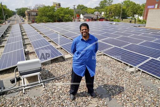 Bishop Richard Howell poses Aug. 19, 2021 beside some of the 630 solar panels on the roof of Shiloh Temple International Ministries in Minneapolis The church is one of many "community solar" providers popping up around the U.S. as surging demand for renewable energy inspires new approaches. Aug. 19, 2021, in Minneapolis. (AP Photo/Jim Mone)