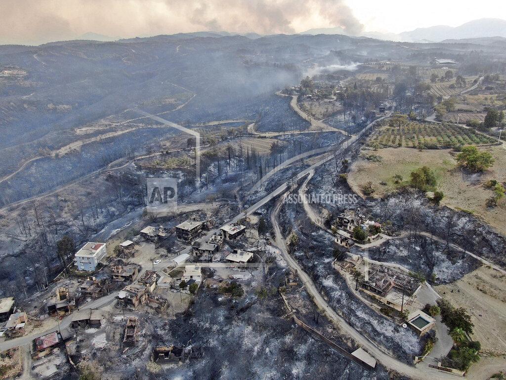 Suat Metin An aerial photo shows destroyed houses in a village as wildfire continue to rage the forests near the Mediterranean coastal town of Manavgat, Antalya, Turkey, Thursday, July 29, 2021. Authorities evacuated homes in southern Turkey as a wildfire fanned by strong winds raged through a forest area near the Mediterranean coastal town of Manavgat. District governor Mustafa Yigit said residents of four neighborhoods were moved out of the fire’s path as firefighters worked to control the blaze that broke out Wednesday. It was not immediately clear what caused the fire but authorities said nearby tourist resorts were not affected. (Suat Metin/IHA via AP)