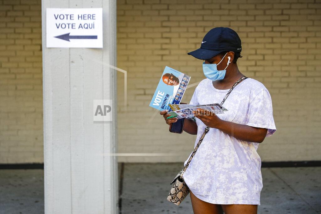 John Minchillo Voters wait in line and read campaign pamphlets at a polling station inside Yonkers Middle/High School, Tuesday, June 23, 2020, in Yonkers, N.Y. (AP Photo/John Minchillo)