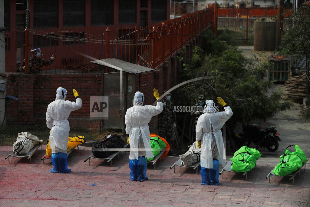 Niranjan Shrestha Nepalese army personnel in PPE suits salute to pay tribute to COVID-19 victims before cremating their bodies near Pashupatinath temple in Kathmandu, Nepal, Friday, May 7, 2021. Across the border from a devastating surge in India, doctors in Nepal warned Friday of a major crisis as daily coronavirus cases hit a record and hospitals were running out of beds and oxygen. (AP Photo/Niranjan Shrestha)