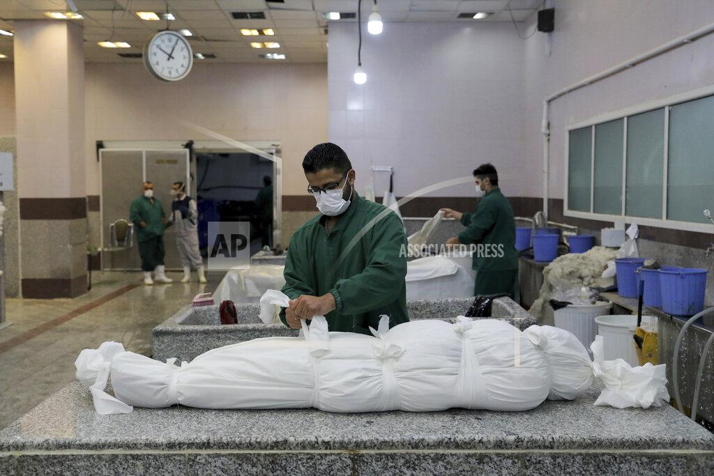Ebrahim Noroozi A cemetery worker prepares the body of a man who died from COVID-19, in a morgue at the Behesht-e-Zahra cemetery on the outskirts of the Iranian capital, Tehran, Iran, Sunday, Nov. 1, 2020. The cemetery is struggling to keep up with the coronavirus pandemic ravaging Iran, with double the usual number of bodies arriving each day and grave diggers excavating thousands of new plots. (AP Photo/Ebrahim Noroozi)