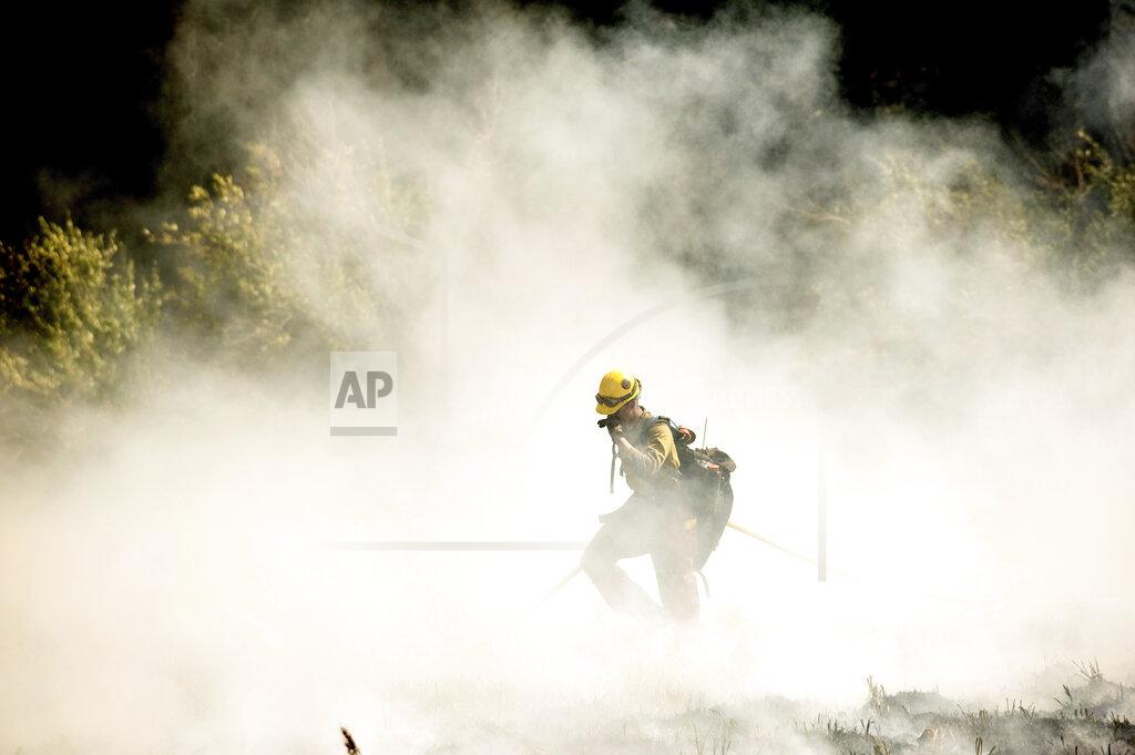 Noah Berger A firefighters battling the Windy Fire extinguishes a spot fire near the Trail of 100 Giants grove of Sequoia National Forest, Calif., on Sunday, Sept. 19, 2021. (AP Photo/Noah Berger)