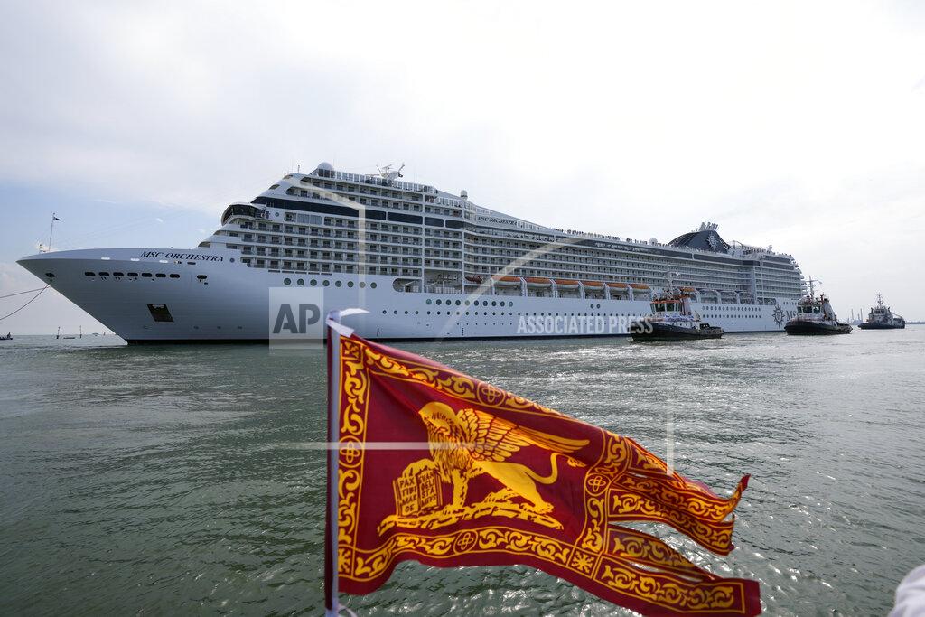 Antonio Calanni The the 92,409-ton, 16-deck MSC Orchestra cruise ship exits the lagoon as a flag of the Lion of St. Mark, the symbol of Venice, is being waved, in Venice, Italy, Saturday, June 5, 2021. The first cruise ship leaving Venice since the pandemic is set to depart Saturday amid protests by activists demanding that the enormous ships be permanently rerouted out the fragile lagoon, especially Giudecca Canal through the city's historic center, due to environmental and safety risks. (AP Photo/Antonio Calanni)
