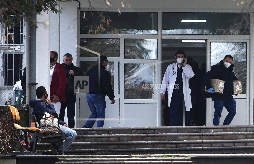 Boris Grdanoski In this picture taken on Tuesday, Dec. 29, 2020, people and health workers are pictured in front of the entrance of the University Clinic complex in Skopje, North Macedonia. When thousands of people across the European Union simultaneously began rolling up their sleeves last month to get a coronavirus vaccination shot, one corner of the continent was left behind, feeling isolated and abandoned: the Balkans. (AP Photo/Boris Grdanoski)