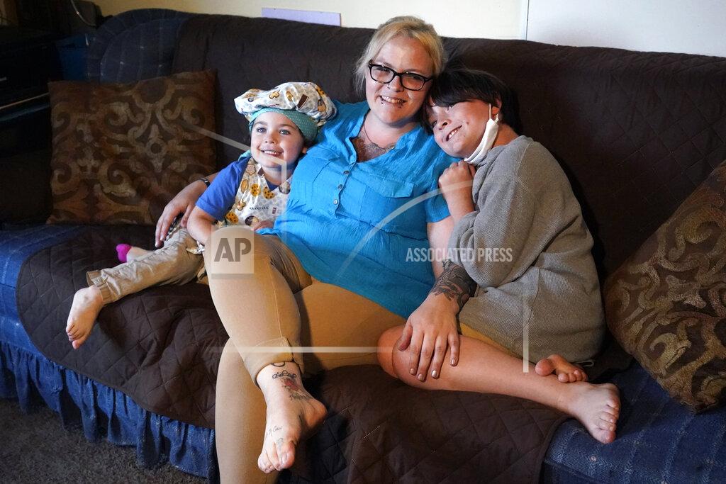 Elise Amendola In this July 28, 2021 photo, Christina Darling and her sons, Brennan, 4, left, and Kayden, 10, pose for a photo at home in Nashua, N.H. Darling and her family have qualified for the expanded child tax credit, part of President Joe Biden's $1.9 trillion coronavirus relief package. "Every step closer we get to a livable wage is beneficial. That is money that gets turned around and spent on the betterment of my kids and myself," said Darling, a housing resource coordinator who had been supplementing her $35,000-a-year salary with monthly visits to the Nashua Soup Kitchen and Shelter's food pantry. (AP Photo/Elise Amendola)