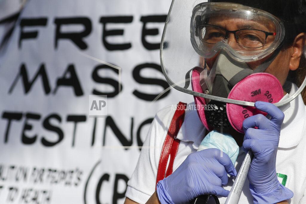 Aaron Favila A health worker wearing protective gear talks during a rally at the Philippine Heart Center in Quezon city, Philippines, Friday Jan. 29, 2021. Protesters said that it has been almost one year since the first reported case of the coronavirus in the country and they are still demanding the government for free mass testing, free vaccines and paid quarantine leave for workers. (AP Photo/Aaron Favila)