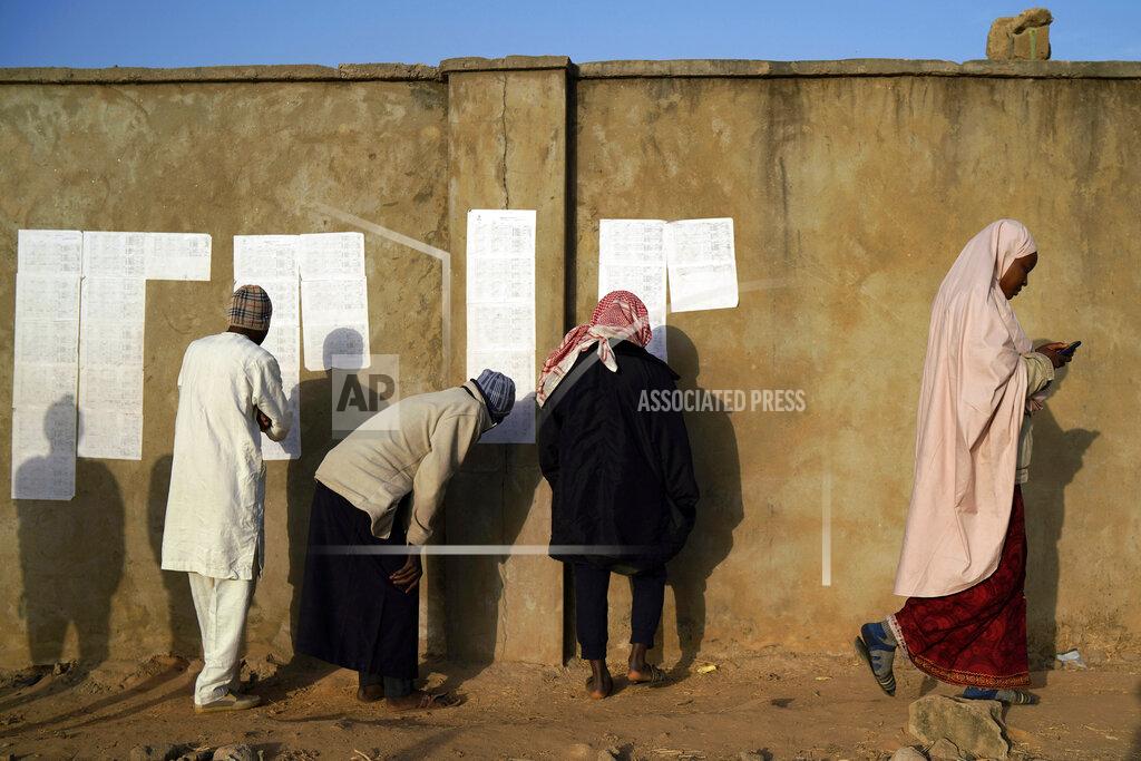 Jerome Delay People check voters lists at a polling station in Kaduna, Nigeria, Saturday, Feb. 16, 2019. Nigeria's electoral commission delayed the presidential election until Feb. 23, making the announcement only five hours before polls were set to open. President Muhammadu Buhari is in a tight race with a former vice president, Atiku Abubakar. Both have signed pledges to contribute to a peaceful election but their supporters have kept up a wave of heated rhetoric. (AP Photo/Jerome Delay)