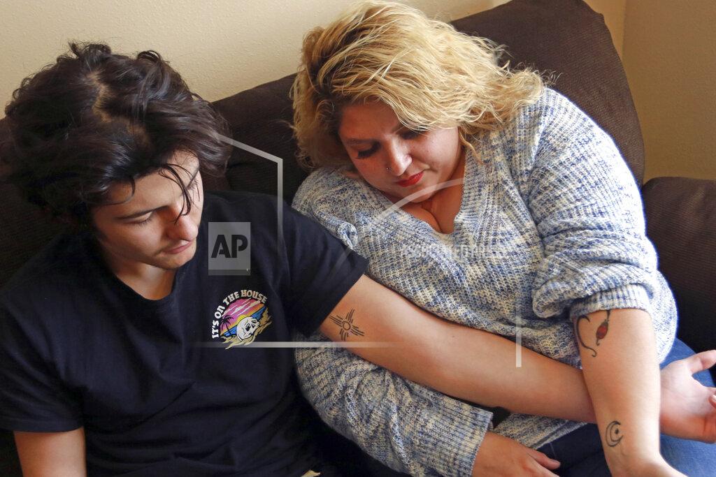Cedar Attanasio Javin Lujan Lopez, 17, a senior at Pojoaque High School, and his mother, Tracy Lujan, show tattoos that they got together, at their home, in Espanola, N.M., Feb, 22, 2021. Tracy Lujan was diagnosed with COVID-19 last fall. (AP Photo/Cedar Attanasio)