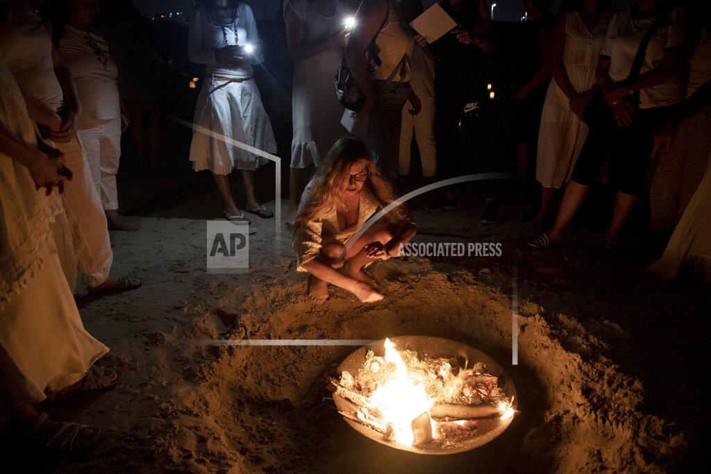 Maya Alleruzzo Women take part in a Tashlich ceremony, where they wrote down things they want to release before casting them into a fire, on the beach in Tel Aviv, Israel, Tuesday, Sept. 14, 2021. Tashlich, which means 'to cast away' in Hebrew, is the practice by which Jews go to a large flowing body of water and symbolically 'throw away' their sins by throwing a piece of bread, or similar food, into the water before the Jewish holiday of Yom Kippur, the holiest day in the Jewish year which starts at sundown Wednesday. (AP Photo/Maya Alleruzzo)
