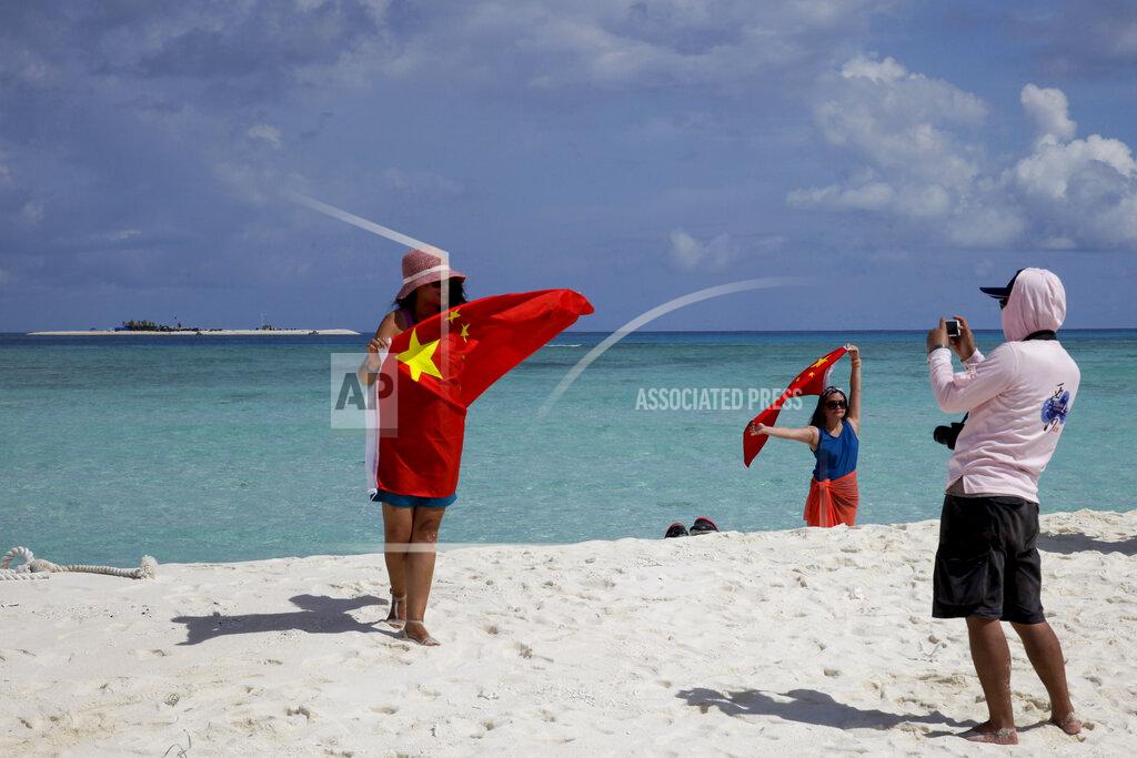 Peng Peng FILE - In this Sept. 14, 2014, file photo, Chinese tourists take souvenir photos with the Chinese national flag as they visit Quanfu Island, one of Paracel Islands of Sansha prefecture of southern China's Hainan province in the South China Sea. China recently announced the establishment of two districts to administer two disputed groups of islands and reefs in the South China Sea to fortify its claim to virtually the entire waterway, among the world’s busiest. One district reportedly covers the Paracel islands and the other has jurisdiction over the Spratlys, the most hotly contested territory in the strategic waters where the Philippines has a presence on at least nine islands and islets and where China has built fortified man-made islands to assert its own claim. (AP Photo/Peng Peng, File)