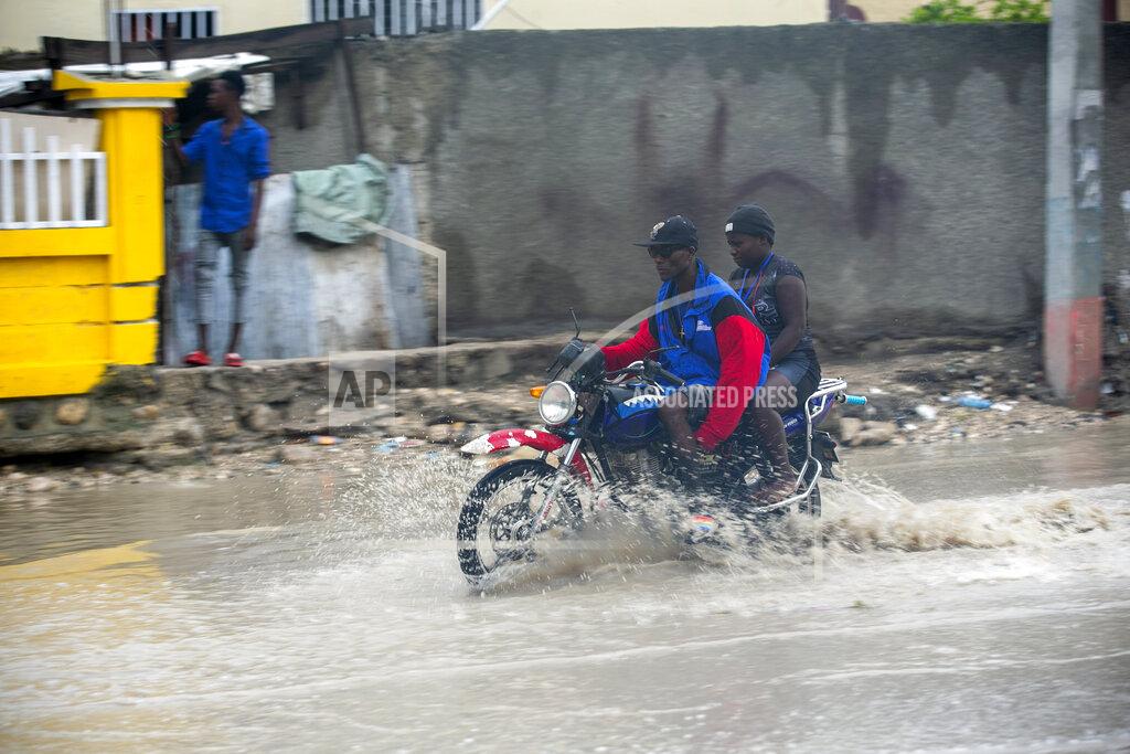 A moto-taxi driver moves through a street flooded by rain brought by the outer bands of Hurricane Isaias, in the Tabarre district of Port-au-Prince, Haiti, early Friday, July 31, 2020. Isaias kept on a path early Friday toward the U.S. East Coast as it approached the Bahamas. (AP Photo/Dieu Nalio Chery)