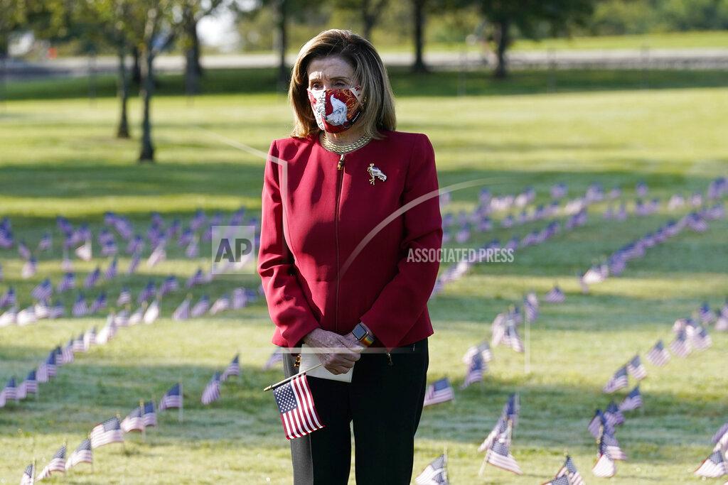 J. Scott Applewhite House Speaker Nancy Pelosi pauses and looks at small flags placed on the grounds of the National Mall by activists from the COVID Memorial Project to mark the deaths of 200,000 lives lost in the U.S. to COVID-19, Tuesday, Sept. 22, 2020 in Washington. (AP Photo/J. Scott Applewhite)