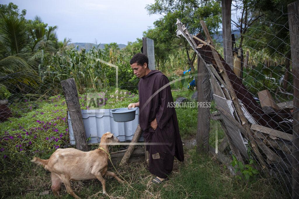 Rodrigo Abd Seminarian Alfredo Santos, 21, brings water to a goat at the drug rehabilitation center in Mission San Francisco de Asis, Honduras, Tuesday, June 29, 2021. A year ago, Brother Santos, who used to go out to pray on the road, was kidnapped, beaten, doused with gasoline and subjected to a simulated hanging. He still is not able to talk about it. (AP Photo/Rodrigo Abd)