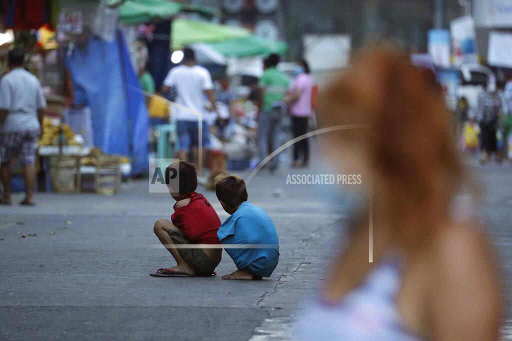 Aaron Favila Boys use their shirts to keep warm as they sit in the middle of the street during stricter health protocols at downtown Manila, Philippines on Wednesday, March 24, 2021. The Philippines has reported more than 677,000 confirmed COVID-19 infections, with nearly 13,000 deaths, the highest totals in Southeast Asia after Indonesia. (AP Photo/Aaron Favila)