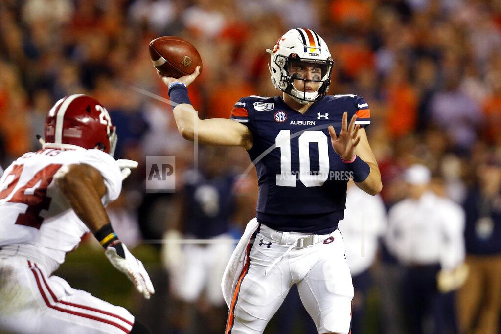 Butch Dill FILE - In this Nov. 30, 2019, file photo, Auburn quarterback Bo Nix (10) throws a pass as Alabama linebacker Terrell Lewis (24) pressures during the second half of an NCAA college football game in Auburn, Ala. Many major universities are determined to forge ahead despite warning signs about the virus, as evidenced by the expanding slate of college football games occurring Saturday. The football-obsessed SEC begins its season with fans in stadiums. (AP Photo/Butch Dill, File)