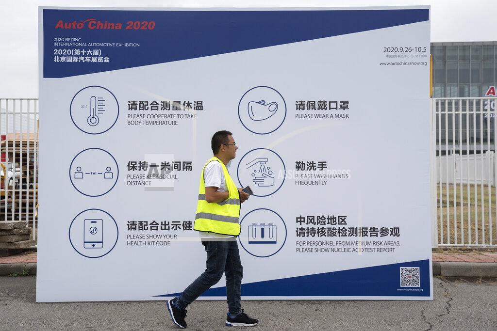 Ng Han Guan A worker passes by regulations to curb the spread of the coronavirus on Thursday, Sept. 24, 2020, aimed for attendees of the upcoming Auto China 2020 show to be held in Beijing. Auto executives are flying in early to wait out a coronavirus quarantine ahead of the Beijing auto show, the year's biggest sales event for a global industry that is struggling with tumbling sales and layoffs. (AP Photo/Ng Han Guan)