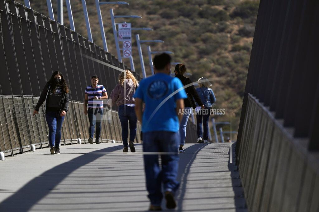 Gregory Bull People walk on a bridge at the San Ysidro Port of Entry, connecting Tijuana, Mexico, to the United States, Wednesday, Oct. 13, 2021, in San Diego. Beleaguered business owners and families separated by COVID-19 restrictions rejoiced Wednesday after the U.S. said it will reopen its land borders to nonessential travel next month, ending a 19-month freeze. (AP Photo/Gregory Bull)