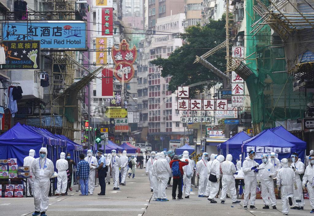 Vincent Yu Government investigators wearing protective suits gather in the Yau Ma Tei area in Hong Kong, Saturday, Jan. 23, 2021. Thousands of Hong Kong residents were locked down Saturday in an unprecedented move to contain a worsening outbreak in the city, authorities said. (AP Photo/Vincent Yu)