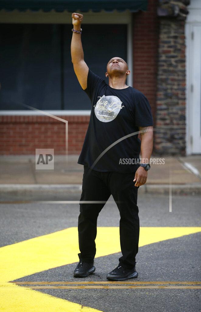 Matt Barnard Ronald Stewart raises his fist while standing over the phrase "Black Lives Matter" painted on the street near the corner of Archer Street and Greenwood Avenue in Tulsa, Okla., on Friday, June 19, 2020. Friday marks Juneteenth, the day in 1865 when federal troops arrived in Galveston, Texas, to take control of the state and ensure all enslaved people be freed more than two years after the Emancipation Proclamation. (Matt Barnard/Tulsa World via AP)