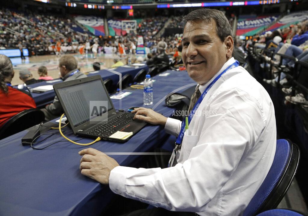 Chuck Burton In this photo taken March 9, 2019 Precision Time inventor Mike Costabile, a former referee, poses for a photo as he keeps track of a log of the system during the second half of an Atlantic Coast Conference women's tournament basketball game in Greensboro, N.C. The Precision Time system created more than two decades ago by Costabile currently is used at nearly every level of the sport, including the NBA and college basketball's NCAA Tournament. Costabile estimates the ability to stop the clock automatically on a referee's whistle can save roughly 90 seconds formerly lost to reaction time when timekeepers manually stopped the clock. (AP Photo/Chuck Burton)