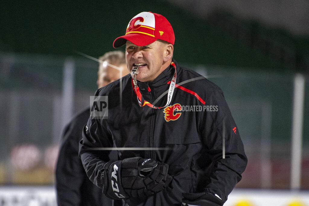 Liam Richards FILE - In this Oct. 25, 2019, file photo, Calgary Flames coach Bill Peters watches practice in Regina, Saskatchewan, ahead of the NHL Heritage Classic outdoor hockey game against the Winnipeg Jets. Calgary Flames general manager Brad Treliving said the team is looking into an accusation that head coach Bill Peters directed racial slurs toward a Nigerian-born hockey player a decade ago in the minor leagues, then arranged for the player’s demotion when he complained. Akim Aliu tweeted Monday, Nov. 25, 2019, that Peters “dropped the N bomb several times towards me in the dressing room in my rookie year because he didn’t like my choice of music.” (Liam Richards/The Canadian Press via AP, File)
