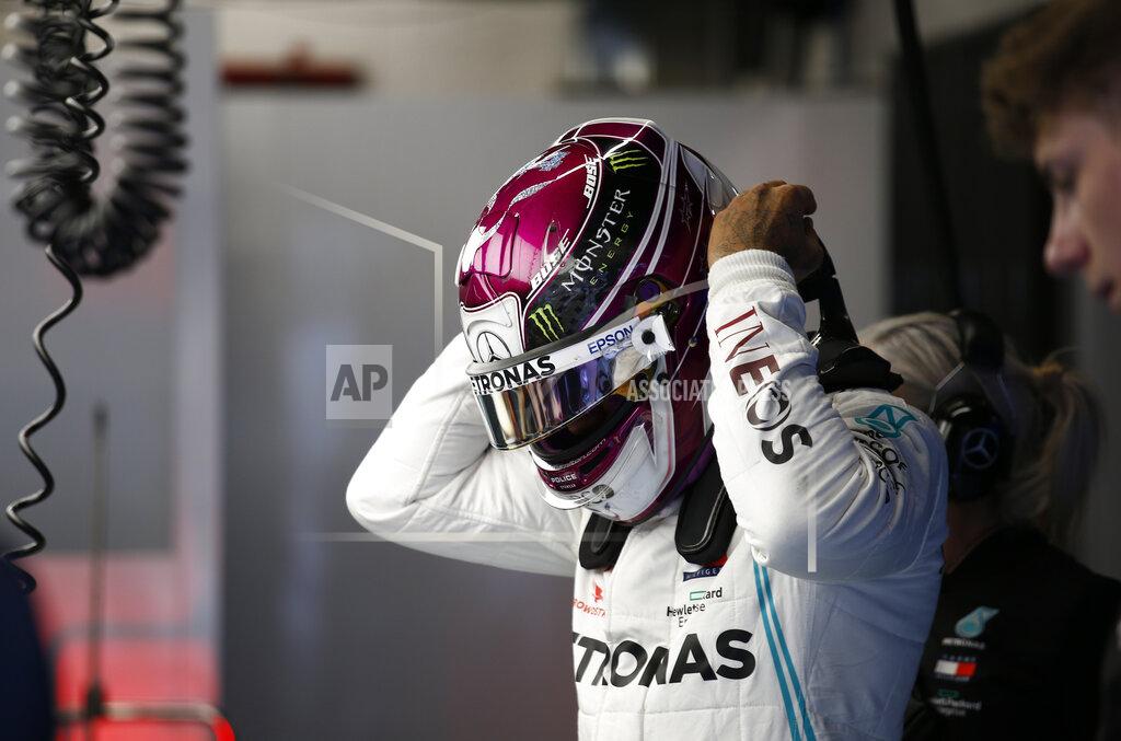 Mercedes driver Lewis Hamilton of Britain adjusts his helmet in the pit lane during the Formula One pre-season testing session at the Barcelona Catalunya racetrack in Montmelo, outside Barcelona, Spain, Friday, Feb. 28, 2020. (AP Photo/Joan Monfort)