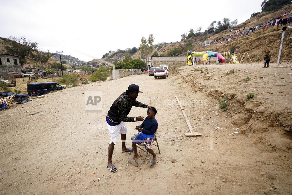 Gregory Bull FILE - Wiggins Nordelus, of Haiti, cuts his son Samuel's hair outside of a shelter for migrants, May 23, 2022, in Tijuana, Mexico. The Supreme Court has ruled that the Biden administration properly ended a Trump-era policy forcing some U.S. asylum-seekers to wait in Mexico. The justices’ 5-4 decision for the administration came in a case about the “Remain in Mexico” policy under President Donald Trump. (AP Photo/Gregory Bull, File)