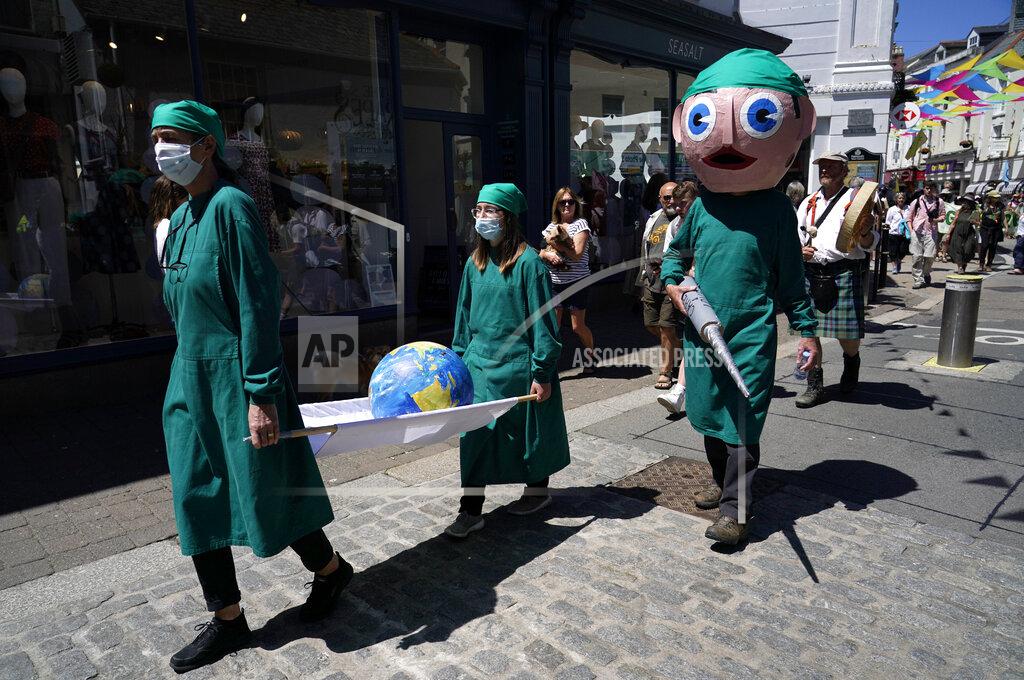 Alberto Pezzali Activists dressed as medical personnel hold a giant syringe and a globe on a stretcher as they march through the streets during a demonstration around the meeting of the G7 in Falmouth, Cornwall, England, Saturday, June 12, 2021. Leaders of the G7 gather for a second day of meetings on Saturday, in which they will discuss COVID-19, climate, foreign policy and the economy. (AP Photo/Alberto Pezzali)