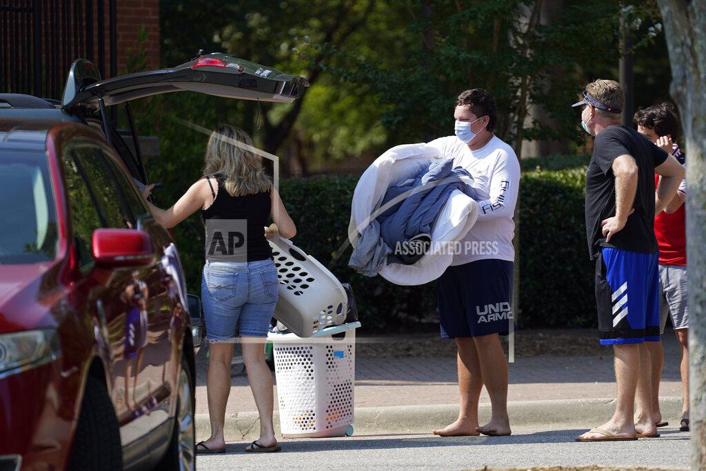 FILE - In this Thursday, Aug. 27, 2020, file photo, students and parents begin to move students' belongings out of Bragaw Residence Hall at North Carolina State University, in Raleigh, N.C. More than 1,000 students at N.C. State have tested positive for the coronavirus since classes began in August. (AP Photo/Gerry Broome, File)