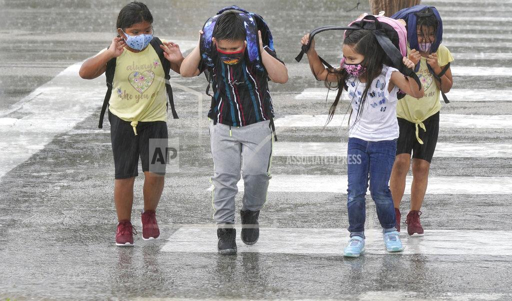 Lm Otero Elementary school children wear masks as they make their way across the street after school let out during a rain storm in Richardson, Texas, Wednesday, Sept. 9, 2020. Many schools across Texas resumed face to face classes this week. (AP Photo/LM Otero)