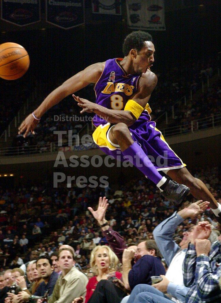 FILE - In this Dec. 20, 2001, file photo Los Angeles Lakers' Kobe Bryant jumps over a row of fans after saving the ball from going out of bounds in the second half of the Lakers 107-101 win over the Houston Rockets in Houston. Bryant, a five-time NBA champion and a two-time Olympic gold medalist, died in a helicopter crash in California on Sunday, Jan. 26, 2020. (AP Photo/Pat Sullivan, file)