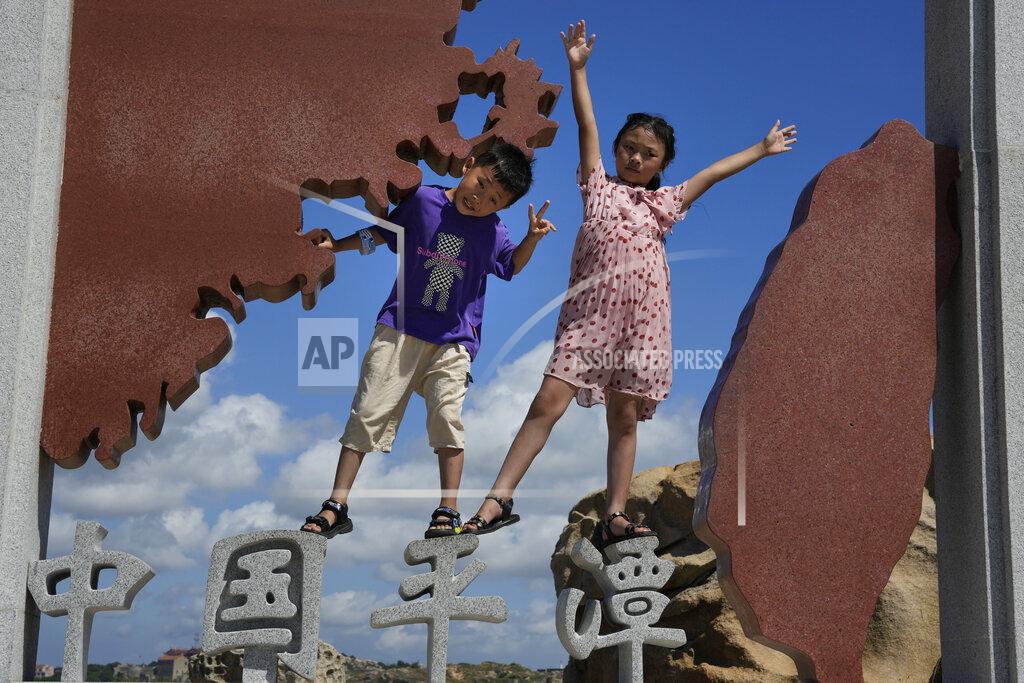 Ng Han Guan Children pose for photos at the 68-nautical-mile scenic spot, the closest point in mainland China to the island of Taiwan, in Pingtan in southeastern China's Fujian Province, Friday, Aug. 5, 2022. China conducted "precision missile strikes" Thursday in waters off Taiwan's coasts as part of military exercises that have raised tensions in the region to their highest level in decades following a visit by U.S. House Speaker Nancy Pelosi. (AP Photo/Ng Han Guan)