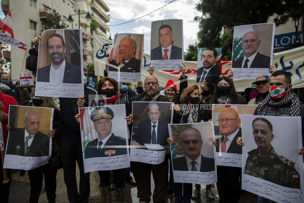 Hassan Ammar FILE - In this Nov. 26, 2020 file photo, anti-government protesters hold pictures of Lebanese leaders during a protest, in Beirut's Ashrafieh district, Lebanon. A public feud in recent weeks among prosecutors has starkly demonstrated how Lebanon's system of sectarian factions is paralyzing Lebanon's judicial system and snarling attempts to root out corruption. (AP Photo/Hassan Ammar, File)