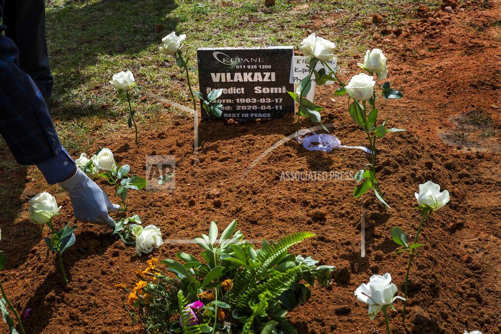 Jerome Delay A relative places a rose on the grave of Benedict Somi Vilakasi following his funeral ceremony at the Nasrec Memorial Park outside Johannesburg Thursday, April 16, 2020. Vilakasi, a Soweto coffee shop manager, died of Covid-19 infection in a Johannesburg hospital Sunday April 12 2020. South Africa is under a strict five-week lockdown in a effort to fight the Coronavirus pandemic. (AP Photo/Jerome Delay)
