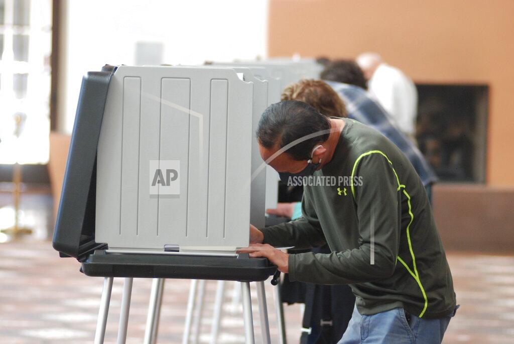 Will Halm, foreground, joins a steady stream of voters to participate in the first day of balloting in New Mexico, at the Santa Fe Convention Center on Tuesday, Oct. 6, 2020, in Santa Fe. Halm said he voted in-person and early to ensure his ballot counts and avoid crowds as a safety precaution against COVID-19. Election officials are witnessing a massive surge in absentee ballot requests. (AP Photo/Morgan Lee)