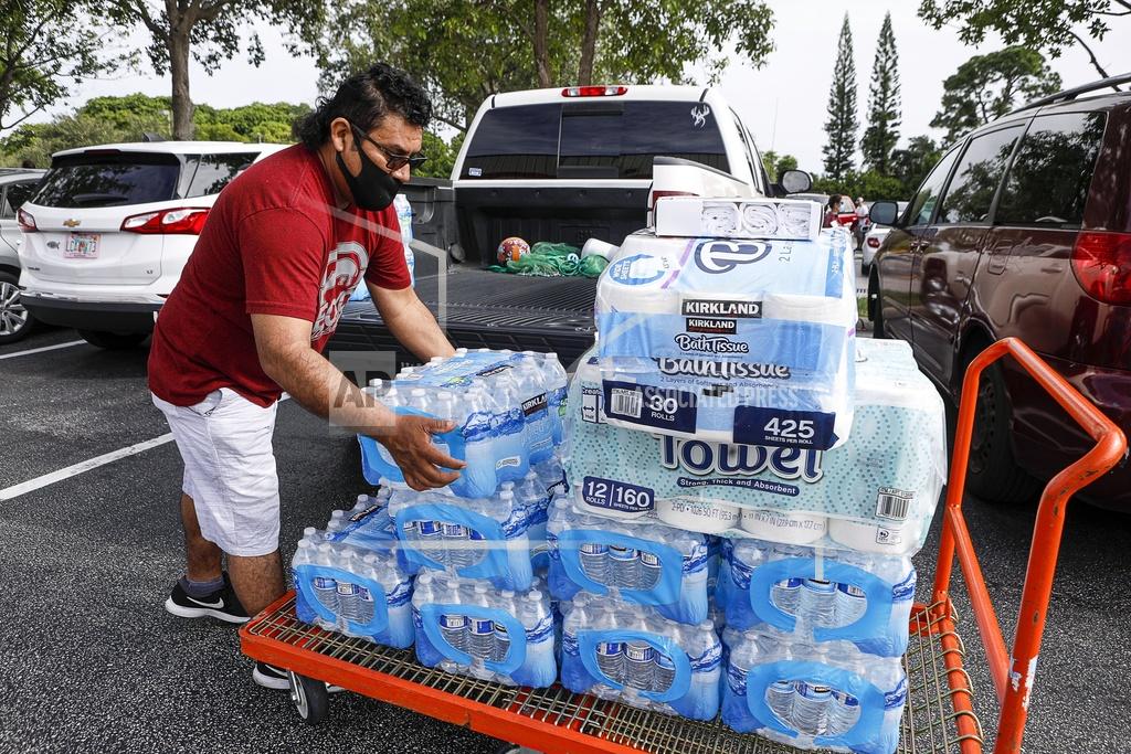 Damon Higgins Lake Worth, Fla., resident Juan Avila stocks up on water and paper towels at the Lantana, Fla Costco as Hurricane Isaias approaches the Florida coast Saturday, Aug. 1, 2020. Isaias snapped trees and knocked out power as it blew through the Bahamas on Saturday and churned toward the Florida coast, where it is threatening to complicate efforts to contain the coronavirus in a hot spot. (Damon Higgins/The Palm Beach Post via AP)