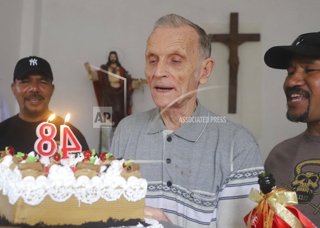 Raimundos Oki Now-defrocked Catholic priest Richard Daschbach, center, is presented a cake during his 84th birthday in Dili, East Timor, on Tuesday, Jan. 26, 2021. While he has his critics, Daschbach’s support appears deep and widespread, extending beyond Oecusse to the capital, Dili. It includes members of the political elite, including former President Xanana Gusmao _ himself an independence hero _ who attended the opening of the trial in February, and this birthday celebration. (AP Photo/Ramundos Oki)