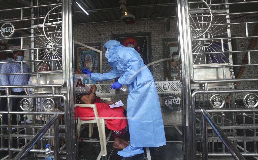 Rafiq Maqbool A health worker takes a swab test of a women at a temple in Mumbai, India, Saturday, July 18, 2020. India crossed 1 million coronavirus cases on Friday, third only to the United States and Brazil, prompting concerns about its readiness to confront an inevitable surge that could overwhelm hospitals and test the country's feeble health care system. (AP Photo/Rafiq Maqbool)