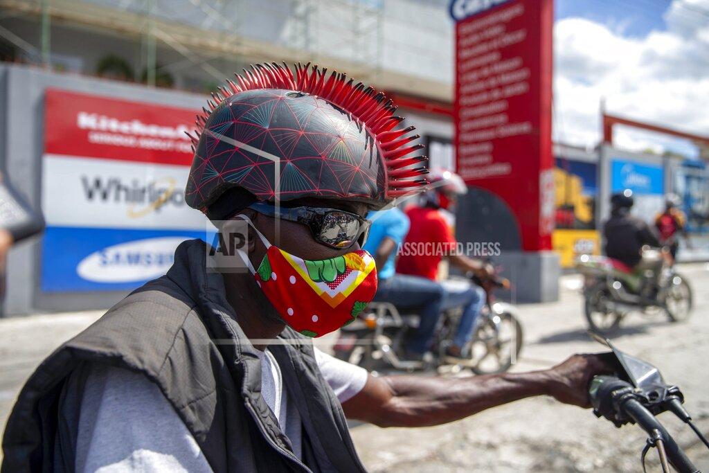 Dieu Nalio Chery A motorcyclist wears a protective face mask and a mohawk helmet as he takes part in a protest to demand the resignation of President Jovenel Moise in Port-au-Prince, Haiti, Saturday, Oct. 17, 2020. The country is currently experiencing a political impasse without a parliament and is now run entirely by decree under Moise. ( AP Photo/Dieu Nalio Chery)